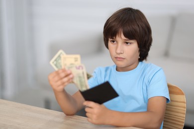 Photo of Boy with pocket money at wooden table indoors