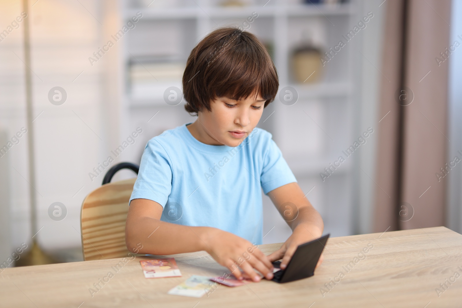 Photo of Boy with pocket money at wooden table indoors