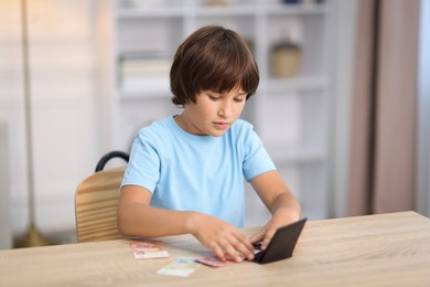 Photo of Boy with pocket money at wooden table indoors