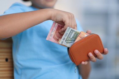 Photo of Boy putting his pocket money into wallet at home, closeup