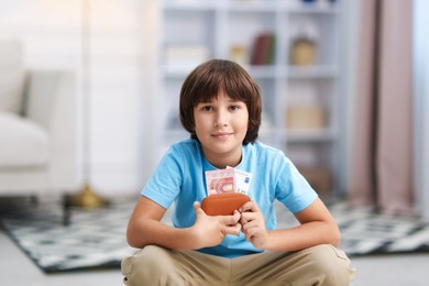 Photo of Boy with pocket money on floor at home