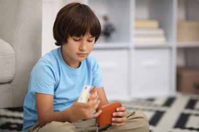 Photo of Boy with pocket money on floor at home. Space for text