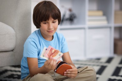 Photo of Boy with pocket money on floor at home. Space for text