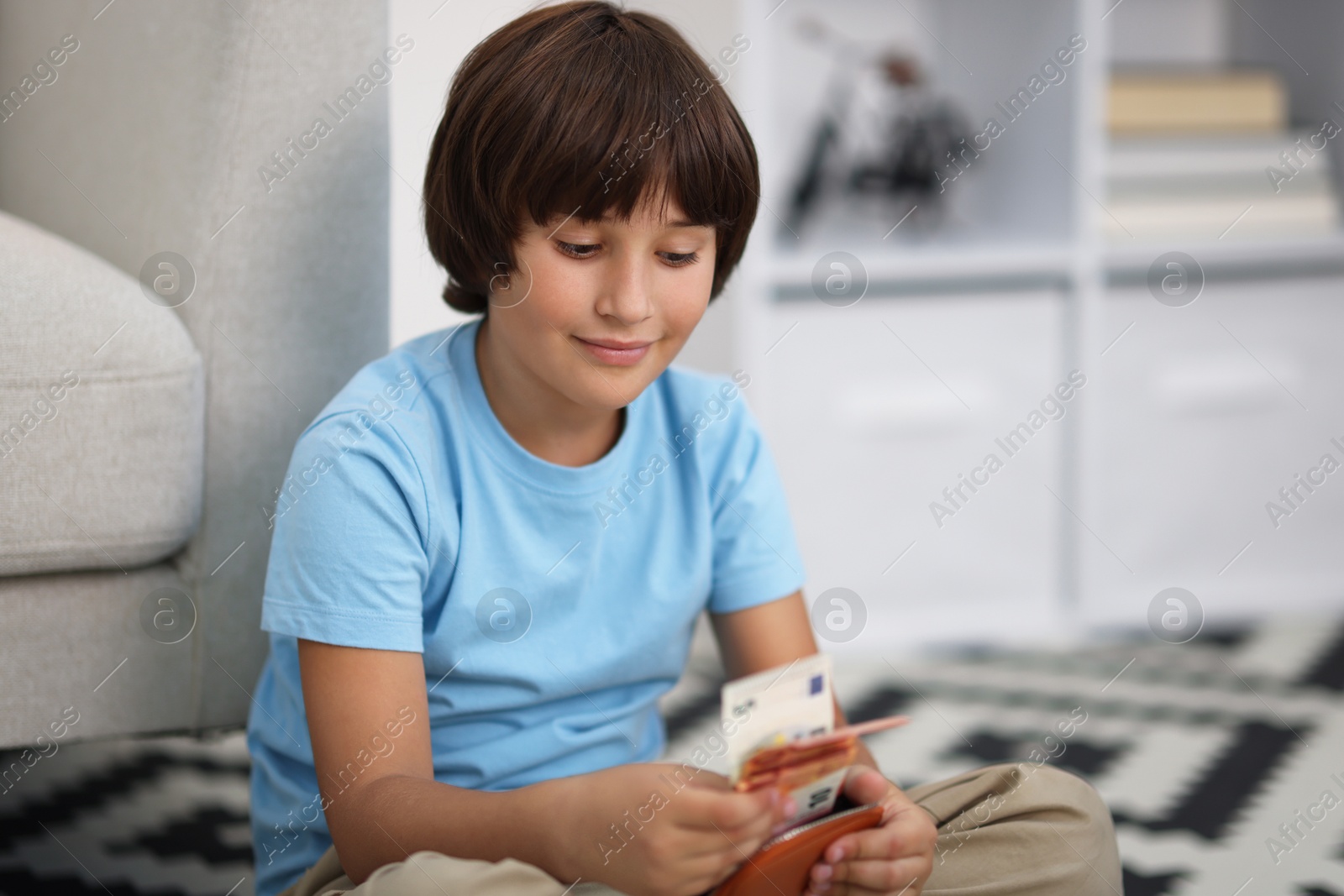 Photo of Boy with pocket money on floor at home. Space for text