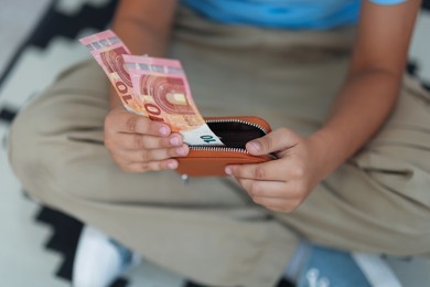 Photo of Boy with pocket money on floor at home, closeup