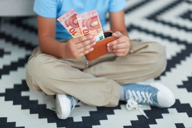 Photo of Boy with pocket money on floor at home, closeup