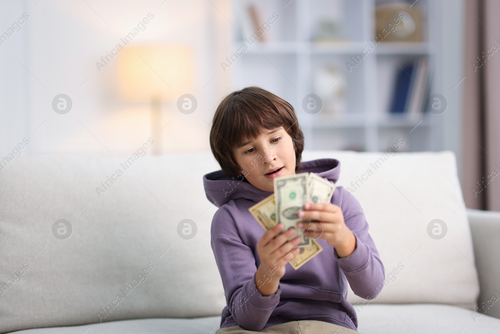 Photo of Boy with pocket money on sofa at home