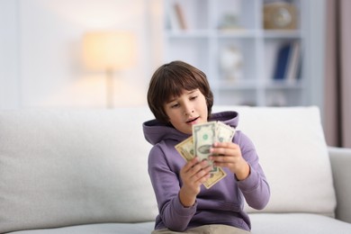 Photo of Boy with pocket money on sofa at home