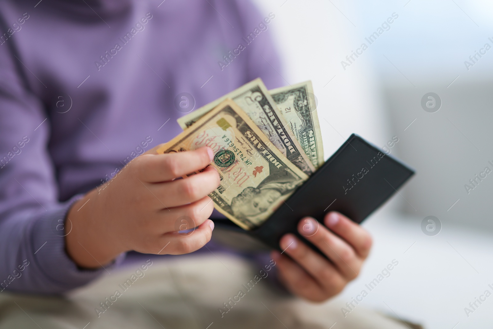 Photo of Boy putting his pocket money into wallet at home, closeup