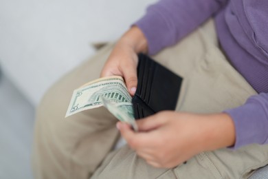 Photo of Boy putting his pocket money into wallet at home, closeup