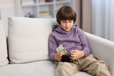 Photo of Boy with pocket money on sofa at home