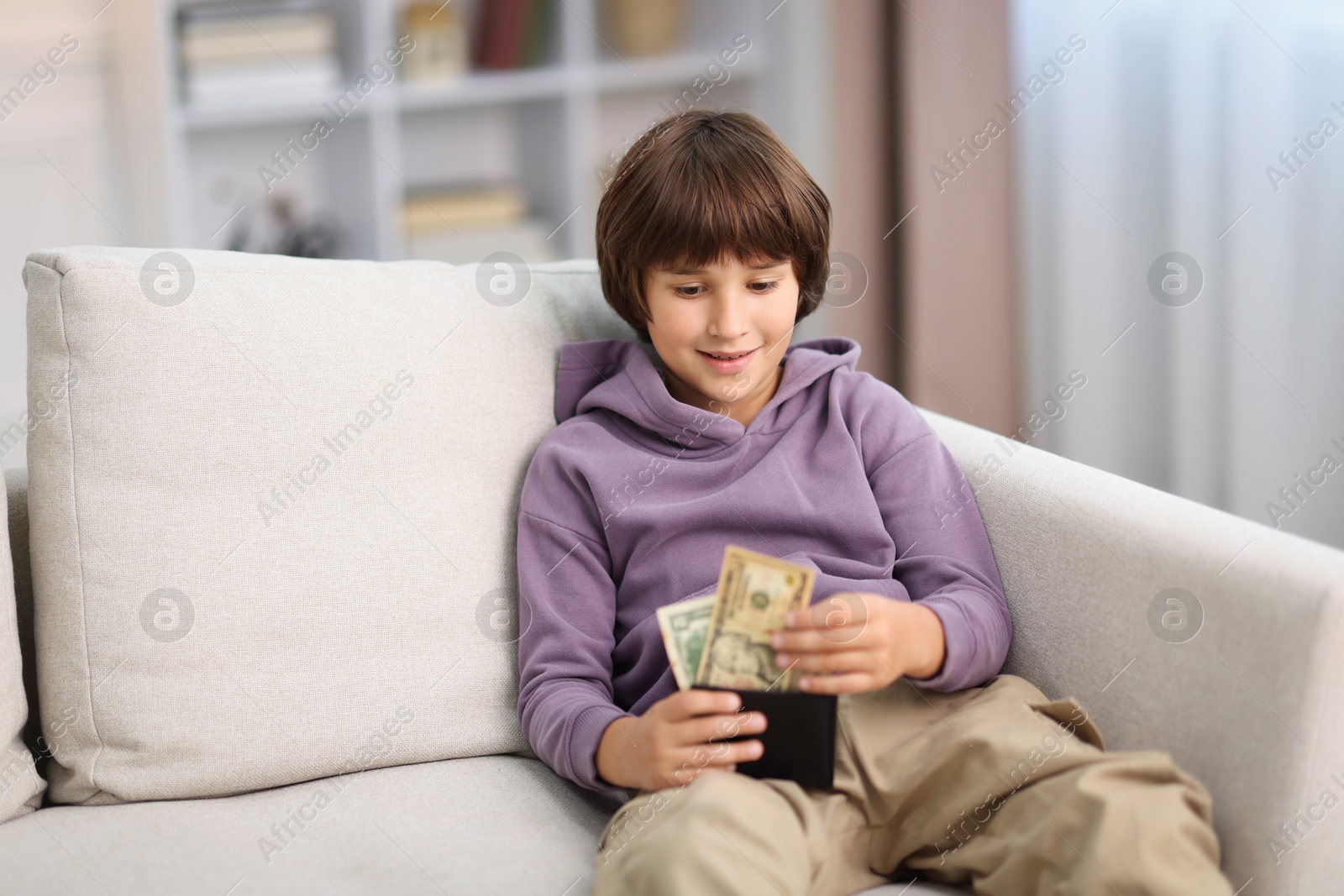Photo of Boy with pocket money on sofa at home