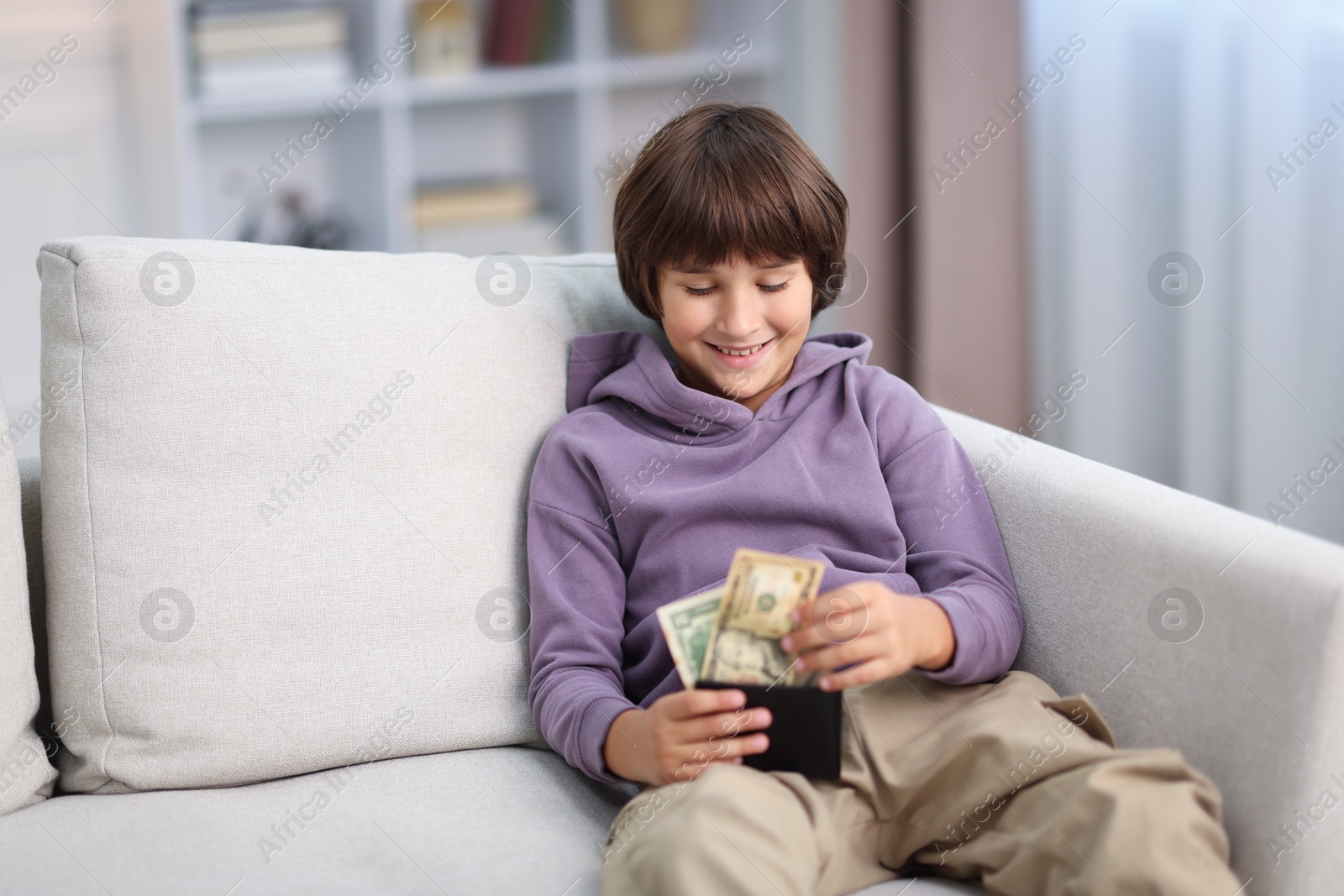Photo of Boy with pocket money on sofa at home
