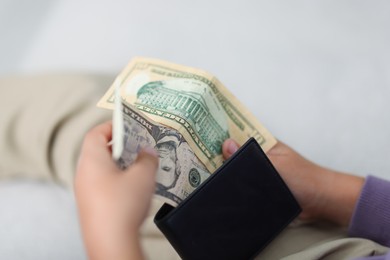 Photo of Boy putting his pocket money into wallet at home, closeup