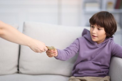 Photo of Mother giving her son pocket money at home, closeup
