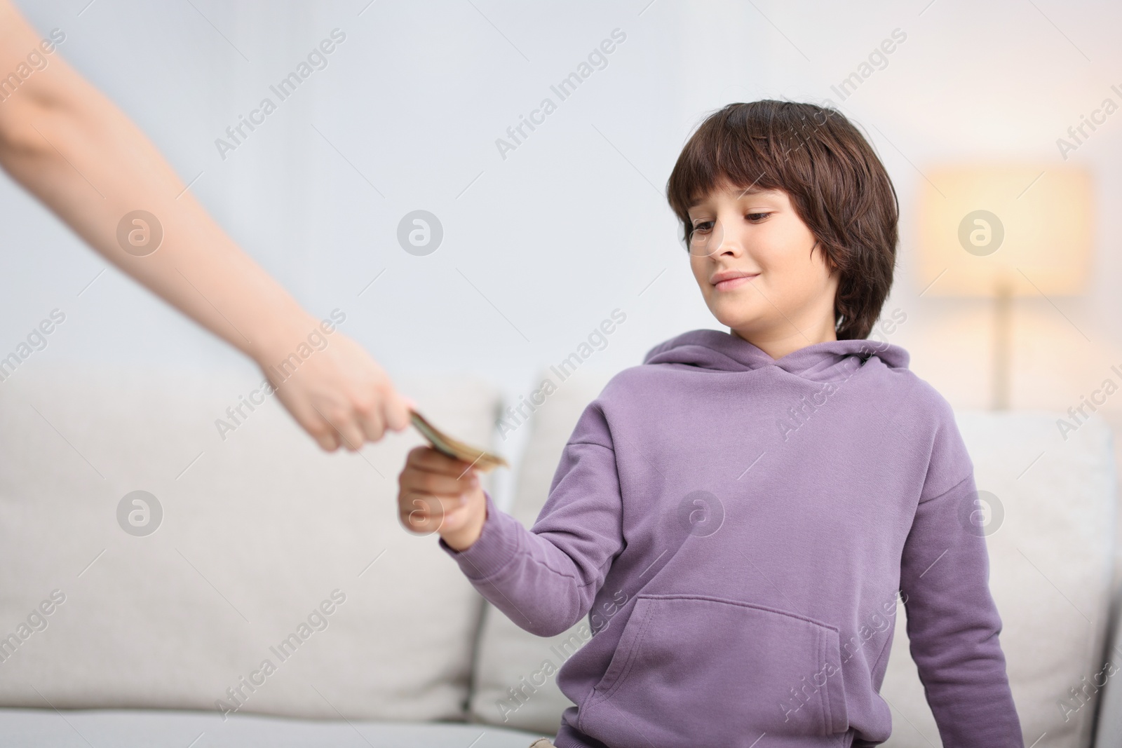 Photo of Mother giving her son pocket money at home, closeup