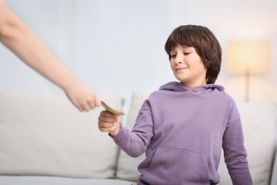 Photo of Mother giving her son pocket money at home, closeup