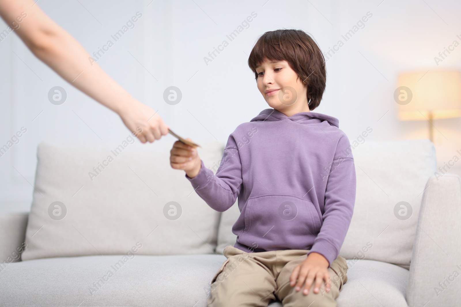 Photo of Mother giving her son pocket money at home, closeup