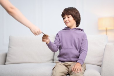 Photo of Mother giving her son pocket money at home, closeup