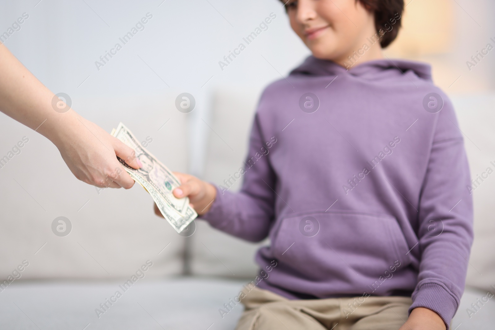 Photo of Mother giving her son pocket money at home, closeup