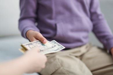 Photo of Mother giving her son pocket money at home, closeup