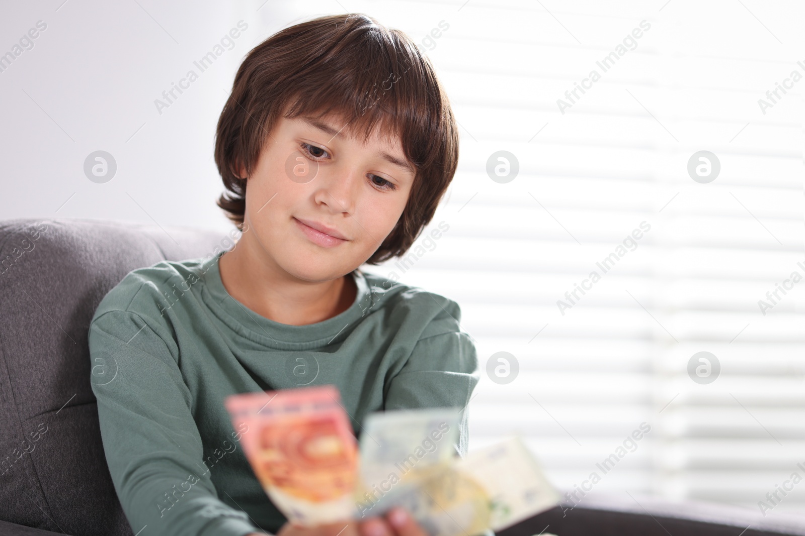 Photo of Boy with pocket money in armchair at home. Space for text