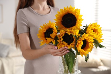 Photo of Teenage girl with beautiful sunflowers at home, closeup