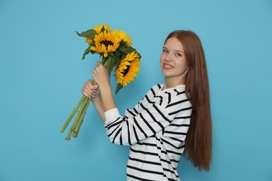 Photo of Teenage girl with bouquet of beautiful sunflowers on light blue background