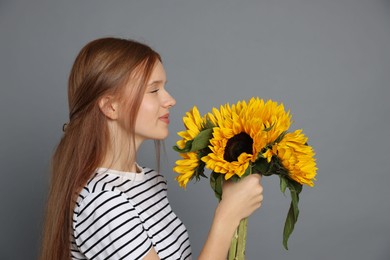 Photo of Teenage girl with bouquet of beautiful sunflowers on grey background