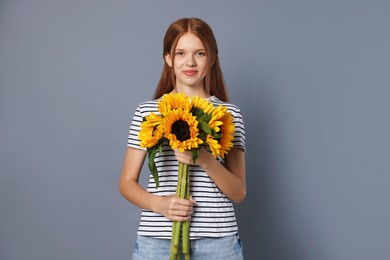 Photo of Teenage girl with bouquet of beautiful sunflowers on grey background