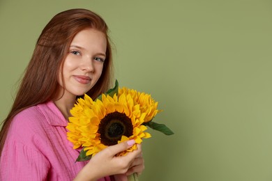 Photo of Teenage girl with beautiful sunflowers on green background, space for text