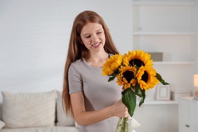 Photo of Teenage girl with beautiful sunflowers at home