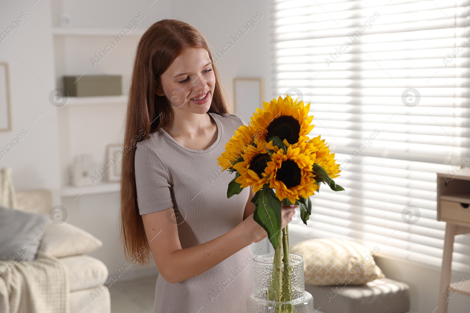 Photo of Teenage girl with beautiful sunflowers at home