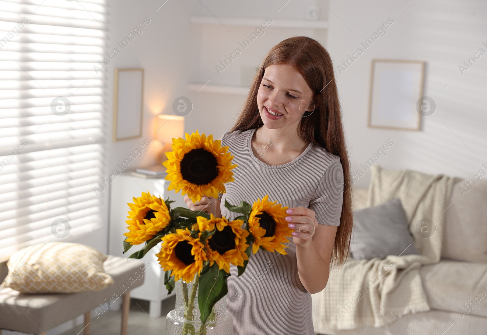 Photo of Teenage girl with beautiful sunflowers at home