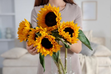 Photo of Teenage girl with beautiful sunflowers at home, closeup