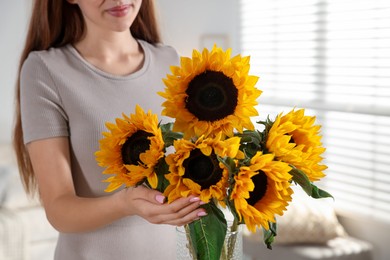 Photo of Teenage girl with beautiful sunflowers at home, closeup