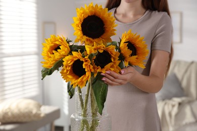Photo of Teenage girl with beautiful sunflowers at home, closeup
