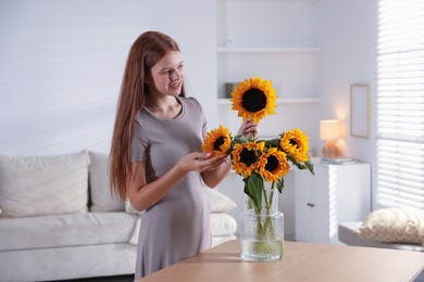 Photo of Teenage girl with beautiful sunflowers at home