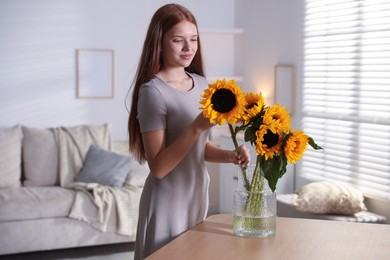 Photo of Teenage girl with beautiful sunflowers at home