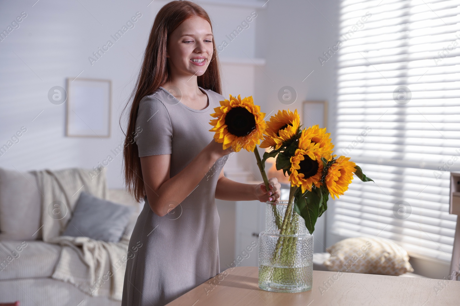 Photo of Teenage girl with beautiful sunflowers at home
