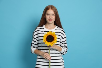 Photo of Teenage girl with sunflower on light blue background