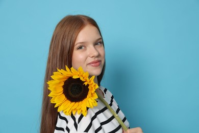 Photo of Teenage girl with sunflower on light blue background