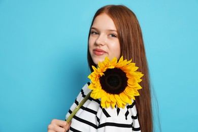 Photo of Teenage girl with sunflower on light blue background