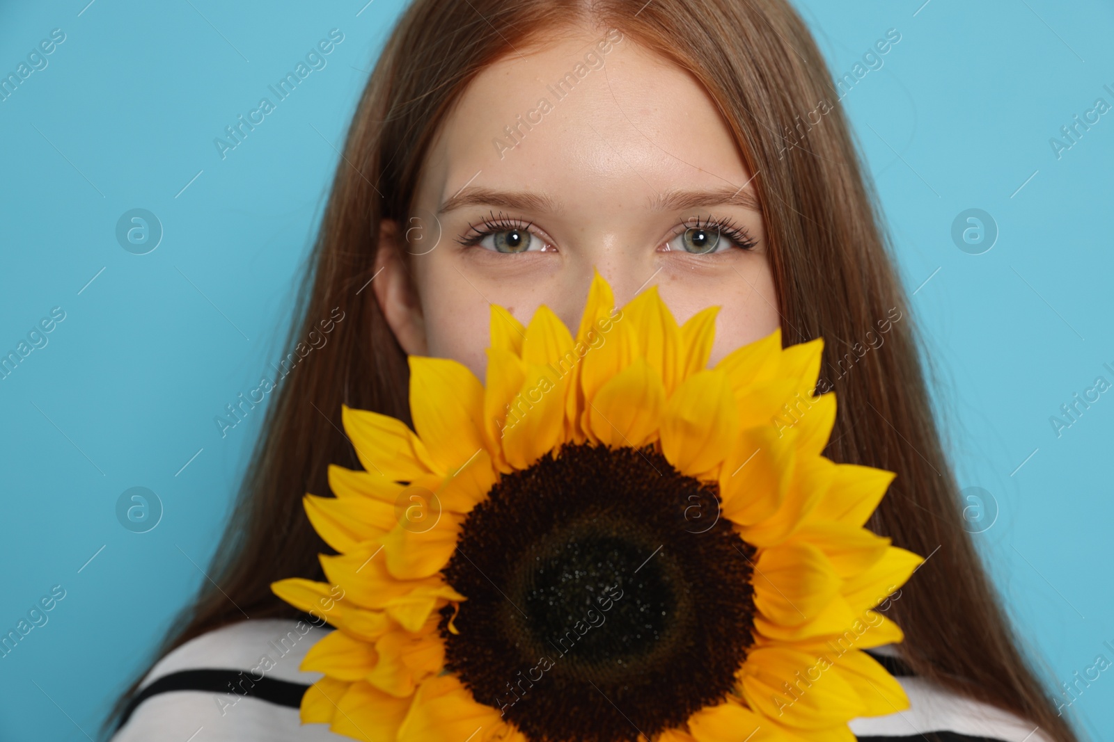 Photo of Teenage girl with sunflower on light blue background