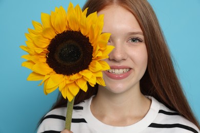 Photo of Teenage girl with sunflower on light blue background