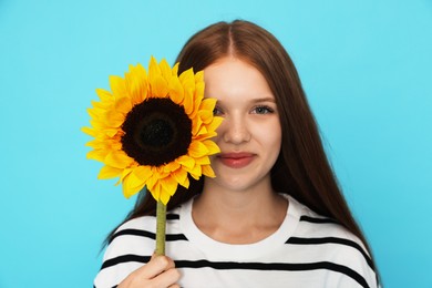 Photo of Teenage girl with sunflower on light blue background