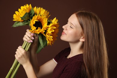 Photo of Teenage girl with bouquet of beautiful sunflowers on brown background