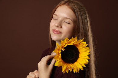 Photo of Teenage girl with beautiful sunflower on brown background