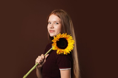Photo of Teenage girl with beautiful sunflower on brown background