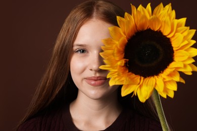 Photo of Teenage girl with beautiful sunflower on brown background